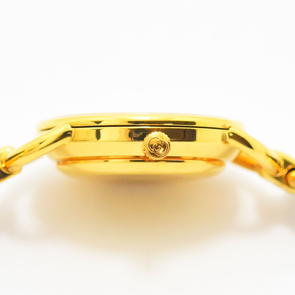 VINTAGE WATCHES FASHIONのグッチのヴィンテージレディース腕時計、ゴールドトーンのラウンドケース側面とロゴ入りリューズのクローズアップ