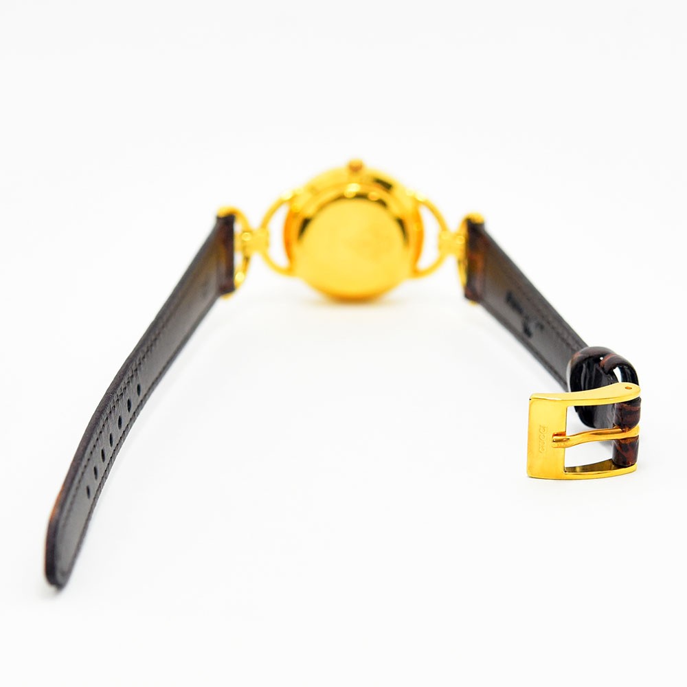 VINTAGE WATCHES FASHIONのGucciヴィンテージレディース腕時計。ゴールドトーンのラウンドケースとブラウンの型押しレザーベルトの背面。
